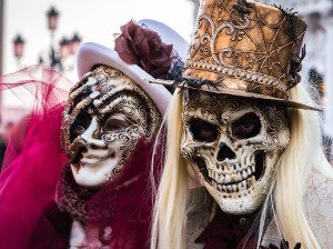 Image of 2 carnival goes wearing skeleton masks and hats. The image is rectangular with a hard border.